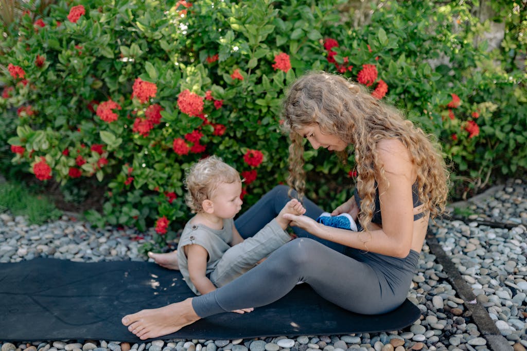 A mother and child enjoy a serene yoga session on a mat amidst a lush garden.
